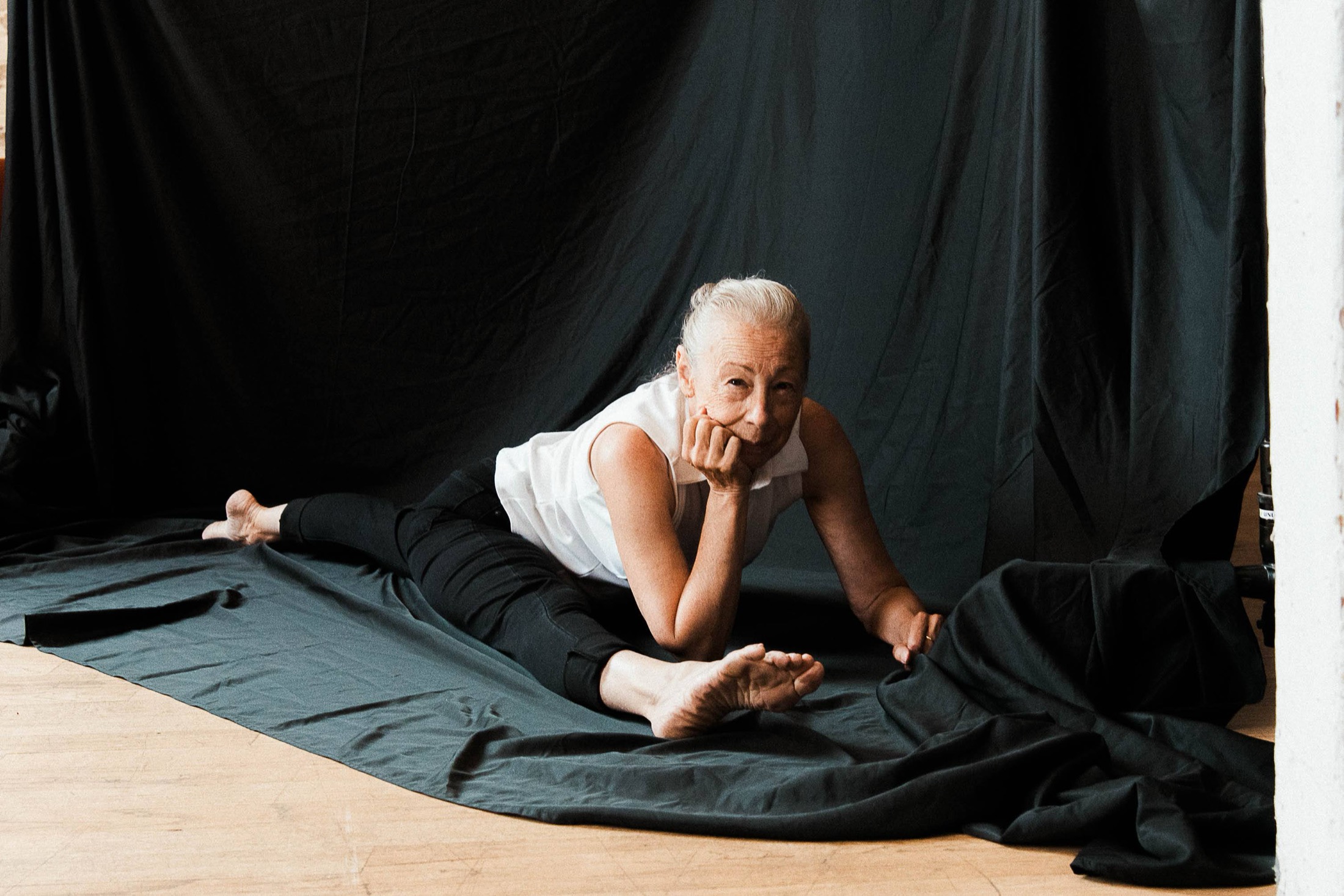Debbie Wilson resting her chin on her hand while sitting in a relaxed split.